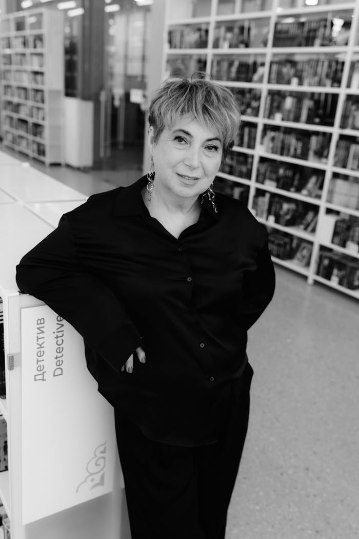 services-05 Black and white portrait of a stylish senior woman posing confidently in a library setting.